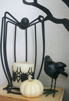 a black bird is standing next to a candle holder with a spider web on it