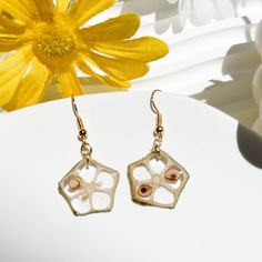 a pair of earrings sitting on top of a white table next to a yellow flower