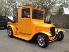 an old yellow truck parked in a parking lot