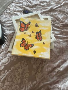 a yellow box with butterflies painted on it sitting on a bed next to a pair of shoes