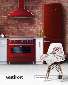 a red stove top oven sitting next to a brick wall in a kitchen with white cabinets