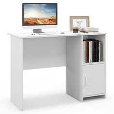 a computer desk with a monitor and books on it, next to a bookcase