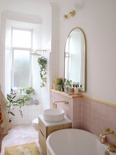 a bath room with a tub a sink and a mirror on the wall next to a window