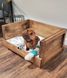 a dog sitting in a wooden bed on the floor