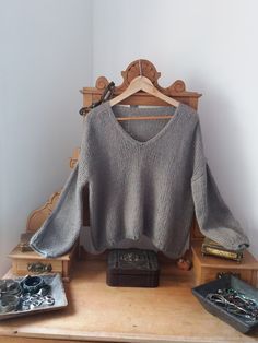 a sweater is sitting on top of a wooden chair next to other items and a remote control