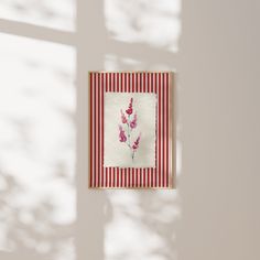 a red and white striped wall hanging on the side of a building with flowers in it