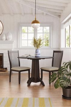 a dining room table with four chairs and a potted plant in the corner next to it