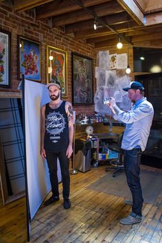 two men standing next to each other in front of a white board with pictures on it