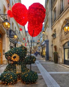 two teddy bears are decorated with lights in the middle of an alleyway between buildings