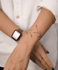 a woman's arm with a flower tattoo on it and a smart phone in her hand