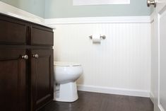 a white toilet sitting next to a wooden cabinet