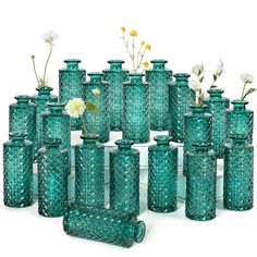 a large group of green vases with flowers in them sitting next to each other