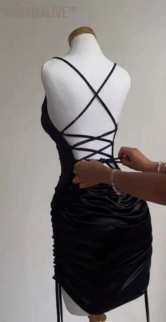 a mannequin with a black dress on it being worked on by a woman