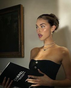 a woman in a black dress holding a book