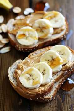 two pieces of bread with peanut butter and banana slices on them sitting on a wooden table