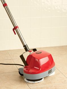 a red and gray floor sweeper sitting on top of a tile floor next to a white tiled wall