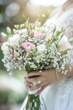 a bride holding a bouquet of white and pink flowers