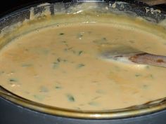 a pan filled with food sitting on top of a stove next to a wooden spoon