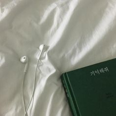 a book and earphones laying on a bed with white sheets in the foreground