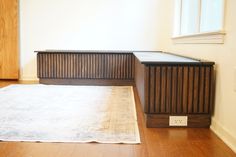 an empty room with a rug on the floor and a wooden cabinet in the corner