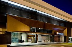 an empty parking lot in front of a large building at night with the lights on