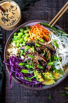 a bowl filled with vegetables and rice next to chopsticks