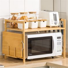 a microwave oven sitting on top of a wooden shelf next to a counter filled with food