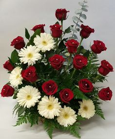 a bouquet of red roses and white daisies in a vase with greenery on the side