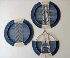 two blue and white plates with tassels hanging on the wall next to each other