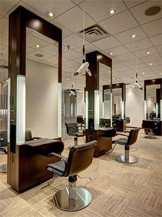 a hair salon with chairs and mirrors on the walls, lights in the ceiling and wood flooring