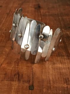 "You will love the way this fabulously unique cuff dresses up your wrist! The inside of this bracelet is a smooth silver band and the outside looks like it's had strips of silver hammered on. This looks like an artisan piece to me. The silver strips are anywhere from 1/2\" to 1 1/2\" long. Please bear in mind that silver is a fairly soft metal, and some of the strips are a bit bent in some areas, but I believe it takes away from the general look of the cuff. Please see all photos for details. I Modern Silver Cuff Bracelets, Modern Silver Cuff Bracelet, Silver Hammered Metal Cuff Bracelet, Modern Hammered Metal Cuff Bracelet, Silver Hammered Cuff Bracelet, Modern Silver Hammered Bracelets, Modern Hammered Silver Bracelets, Contemporary Silver Cuff Bracelets, Silver Hammered Cuff Bangle