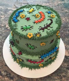 a three tiered cake with green frosting and colorful decorations on the top layer