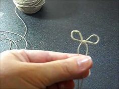 someone is holding a string with a bow on it and thread spools in the background