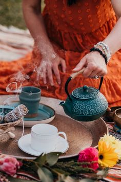 a woman in an orange dress is pouring tea from a teapot on a tray