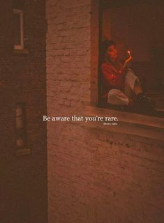 a woman sitting on top of a window sill next to a brick building with the words be aware that you're rare