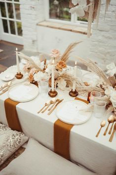 the table is set with candles, plates and napkins for dinner guests to enjoy