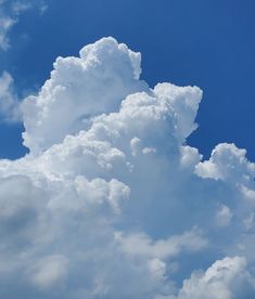 a large cloud is in the sky with blue skies behind it and an airplane flying by