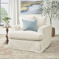 a living room with a white chair and a painting on the wall behind it,