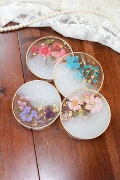 four plates with flowers on them sitting on a wooden floor next to a lace doily