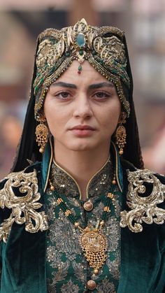 a close up of a woman wearing a green and gold costume with elaborate headdress