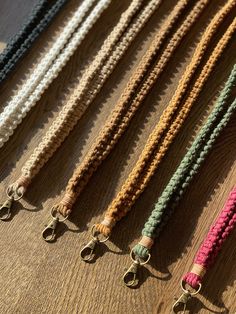 five different colored ropes on a wooden surface with metal clasps attached to the ends