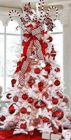 a white christmas tree decorated with red and silver ornaments