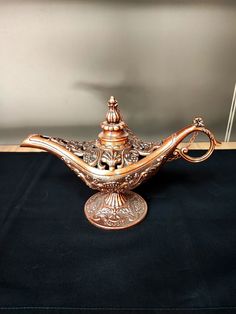 an ornate golden teapot on a black table