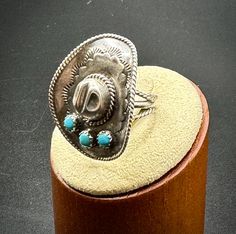 This cool sterling silver cowboy hat ring is highly detailed and sits beautifully on the hand. This silver ring is crowned with 3 blue turquoise stone and the shank as well as the brim of the hat feature twist wire detail. The size of this piece makes it the perfect size for teenagers, as well as women.  It also pairs beautifully with other turquoise and silver jewelry.   Handmade jewelry makes wonderful gifts. This silver ring would make a cool thumb ring for a woman or a teenage girl or a fun Sterling Silver Turquoise Ring With Concho, Western Sterling Silver Turquoise Concho Ring, Silver Turquoise Concho Ring In Sterling Silver, Adjustable Stamped Turquoise Ring In Sterling Silver, Adjustable Stamped Sterling Silver Turquoise Ring, Western Style Turquoise Ring Collectible, Western Blue Jewelry For Rodeo, Western Style Blue Jewelry For Rodeo, Handmade Western Style Silver Turquoise Ring