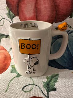 a coffee cup with a cartoon character holding a boo sign on it's side