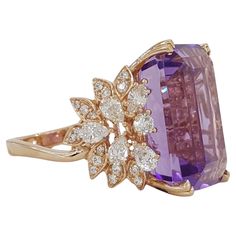 Indulge in luxury with our breathtaking statement ring featuring a stunning 25.85 carat emerald-cut amethyst, adorned with a dazzling array of natural pear, round, and marquise brilliant-cut diamonds. Weighing 13.4 grams and sized perfectly at 7, this ring exudes elegance and sophistication. The vivid purple hue of the natural amethyst, measuring 20.17 x 15.20 x 10.97 mm, captivates the eye, while the 44 diamonds totaling approximately 2 carats in weight add a touch of sparkle. Each diamond boasts G-I color and VS-SI clarity, ensuring exceptional quality. Elevate your style with this exquisite masterpiece. Amathyst Ring, Purple Diamond Ring, Amethyst Cocktail Ring, Yellow Gold Cocktail Ring, Purple Diamond, Gold Cocktail Ring, Gold Cocktail, Fine Jewels, Purple Hues