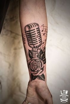 a person's arm with a microphone and rose tattoo on the left side of their arm