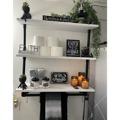 shelves with candles, plants and pictures on them in a bathroom area that is decorated with black and white decor