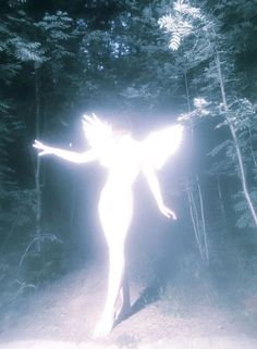 a woman with her arms spread out in the air while standing on a path surrounded by trees