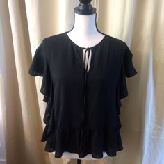 Black Short Sleeve Blouse With Ruffle Along Bottom As Well As On The Arms . Super Cute Black Ruffle Sleeve Top For Work, Black Ruffle Sleeve Blouse For Work, Black Ruffle Sleeve Tops For Night Out, Casual Black Blouse With Ruffle Sleeves, Black Casual Blouse With Ruffle Sleeves, Black Short Sleeve Blouse For Day Out, Black Ruffle Sleeve Blouse For Spring, Black Short Sleeve Blouse With Ruffles, Black Ruffled Blouse With Short Sleeves